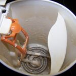 Inside of a white plastic electric kettle with a coiled heating element coated in pale limescale.