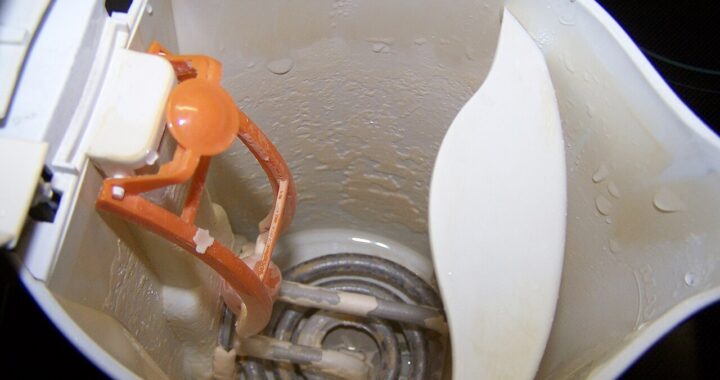 Inside of a white plastic electric kettle with a coiled heating element coated in pale limescale.