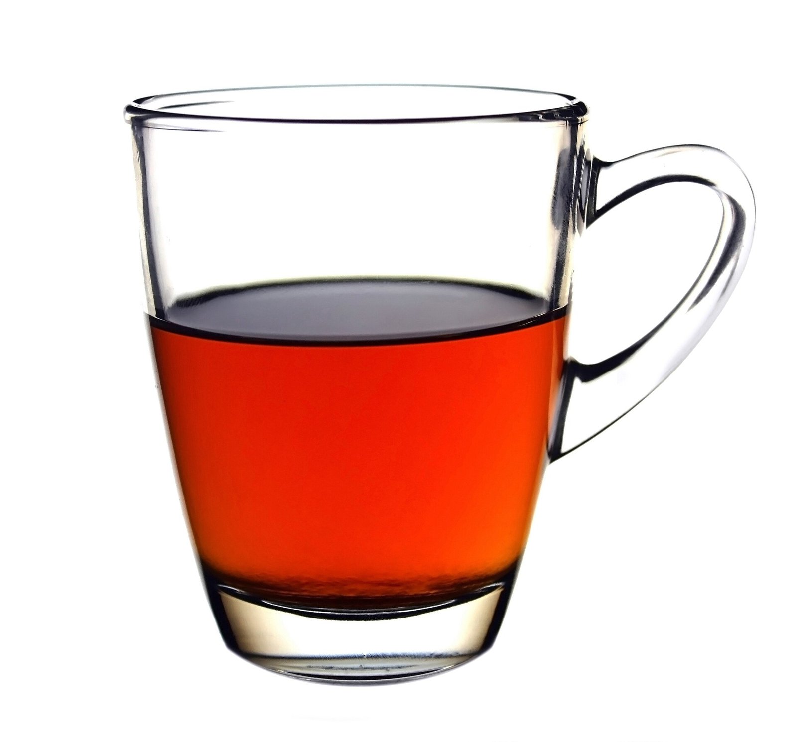 A clear glass mug half full of bright reddish-amber black tea against a white background.