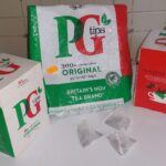 Three boxes of PG Tips tea with pyramid tea bags in front, on a kitchen counter.