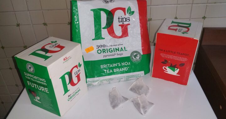 Three boxes of PG Tips tea with pyramid tea bags in front, on a kitchen counter.