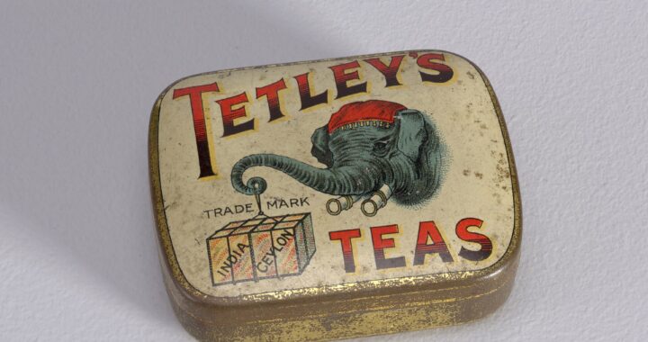 An old tin printed with Tetley's Teas in red and black and an elephant carrying tea chests.