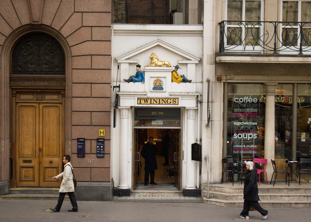 The narrow white Twinings shopfront on the Strand in London with a gold lion above the door.